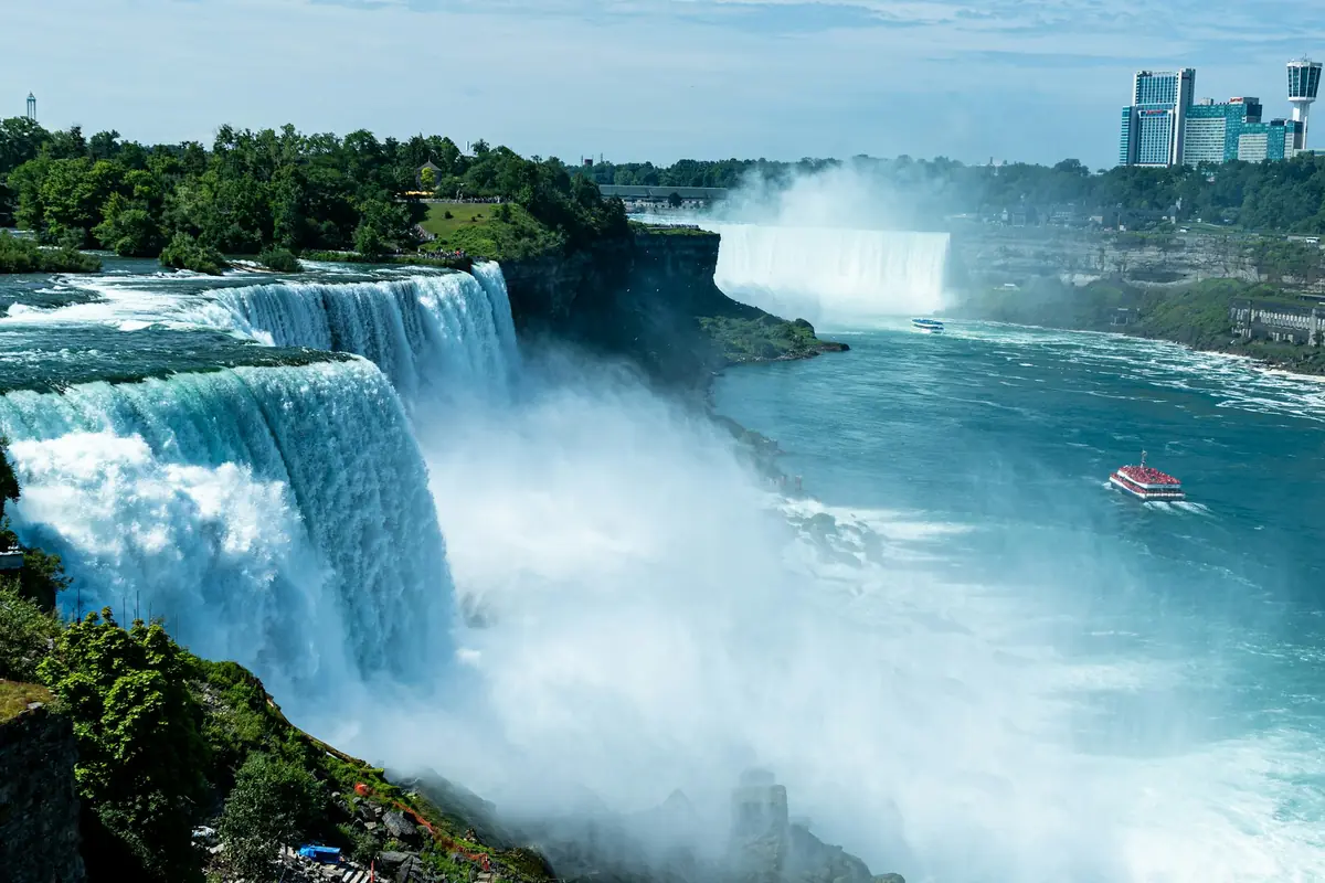 Niagara Falls with a tour boat on the river and the city skyline behind