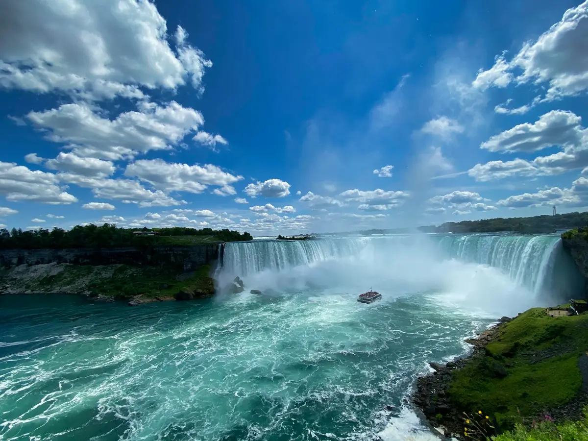 Horseshoe Falls under a blue sky with a tour boat in the mist